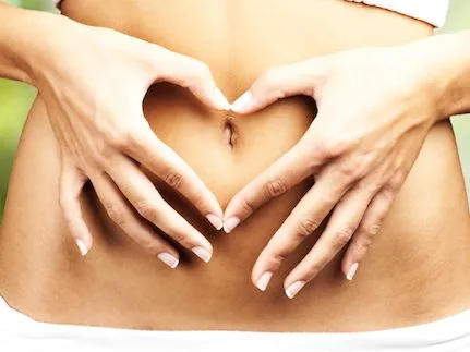 healthy woman doing heart symbol on her belly button at outdoor